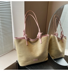 Detailed view of woven straw tote bag with pink leather handles and knot accents