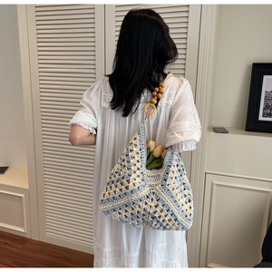 Detail of blue and white crochet tote bag featuring wooden bead handles and floral decor