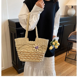 Detailed texture of beige woven straw tote bag with purple floral charm on shoulder