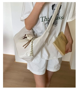 Close-up of a white crocodile-embossed hobo shoulder bag with a plush bear charm