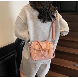 Détail du sac bandoulière en nylon rose avec sangle réglable et fermeture éclair argentée