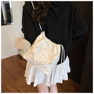 Detailed back view of a white patent leather bucket bag with bows and a chain strap