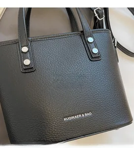 Close-up of black lychee grain texture with silver rivets and brand logo on the bag