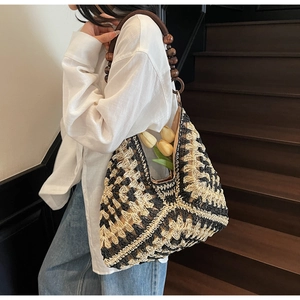 Close-up of geometric crochet tote bag with dark brown wooden bead handle on shoulder
