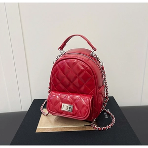 Detailed view of red quilted mini backpack featuring shiny finish and silver chain straps