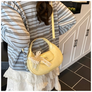 Detail of yellow wrinkled hobo bag with pearl lace bow charm and gold logo detail
