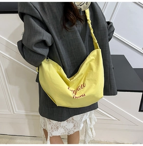 Close-up of vibrant yellow crescent nylon bag featuring trendy pleated strap details