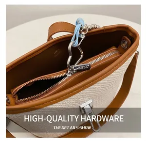 Close-up of woven bucket bag featuring silver KOSY zipper and heart metal charm detail