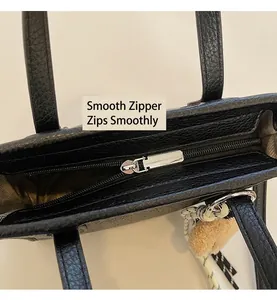 Detail of smooth silver zipper on black pebble leather tote with pink plush charm