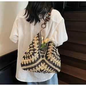 Detail of woven tote bag featuring contrast geometric patterns and wooden bead strap