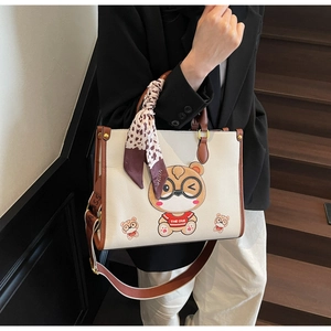 Detail of white leather tote with cartoon bears, brown trim, and silk scarf on handle
