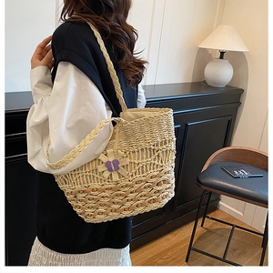 Close-up of the intricate hollow weave pattern and purple bow on the straw tote bag