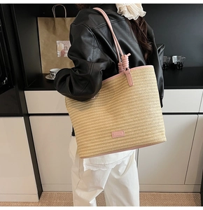 Close-up of minimalist straw beach tote bag with pink leather handles and trim detail
