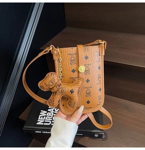 Detail of brown leather crossbody bag with cartoon bear pattern and a cute puppy charm
