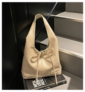Sac hobo chic crème avec un détail de nœud élégant dans un décor urbain et moderne