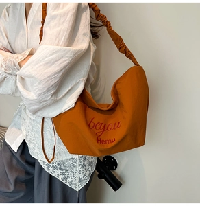 Detail of caramel crescent shoulder bag with pleated strap and beyou Hemu logo print
