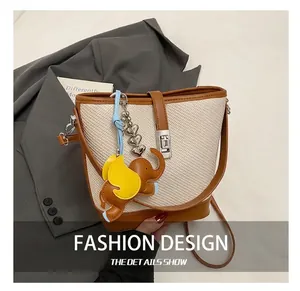Detail of cream woven bucket bag with brown leather trim and cute elephant charm
