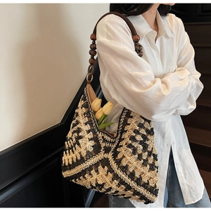 Detail of woven tote bag featuring geometric patterns and unique dark wooden bead strap