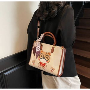 Detail of a large cream tote bag with bear motif and leopard scarf shown on a model
