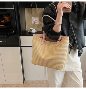 Detail of hand-woven straw tote bag featuring pink leather handles and large capacity
