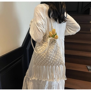 Detail of white handmade macrame tote bag with fringe tassels and woven cotton textures