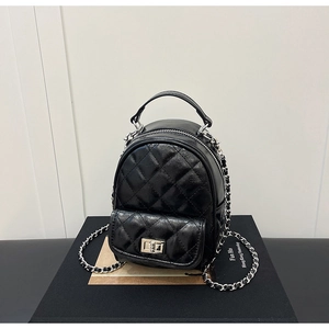 Close-up of black quilted leather mini backpack with silver chain strap and metal lock