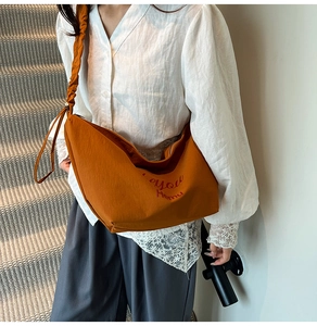 Detail of orange tote bag with ruffled shoulder strap and metallic adjustment bead