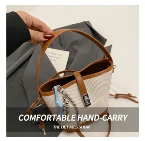 Detailed close-up of woven bucket bag featuring brown leather handle and silver hardware