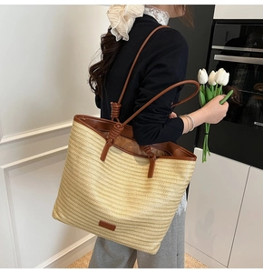 Detail of straw tote bag with brown leather handles and knot decorative accents