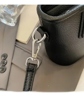 Close-up of silver metal hook hardware on black litchi pattern leather bucket bag