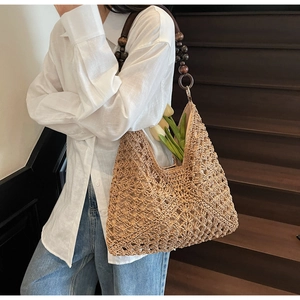 Detail of hand-woven straw tote bag featuring contrast dark wooden bead shoulder straps