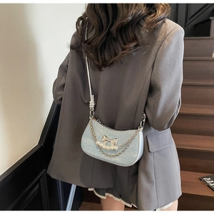 Close-up of sparkling light blue crescent bag featuring silver bow and pearl chain detail