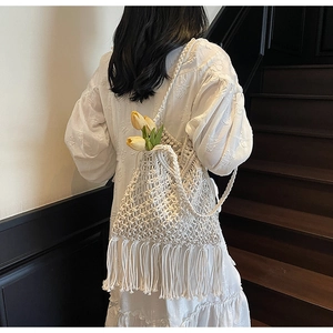 Close-up of bohemian hollow woven tote bag with long tassels and natural cotton texture