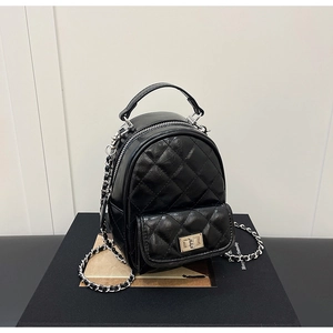 Detail of black quilted leather mini backpack with silver metal twist lock and chain strap