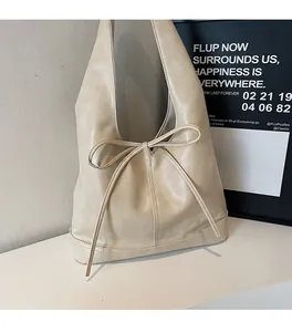 Détail d'un sac cabas en cuir crème avec un nœud décoratif et une large bandoulière