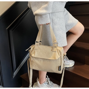 Detail of minimalist beige nylon handbag featuring double handles and durable fabric texture