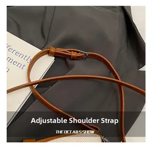 Detail of adjustable brown leather shoulder strap with silver buckle and stitching