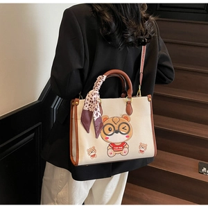 Chic tote bag with bear embroidery and leopard scarf shown on a wooden staircase