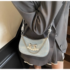Detail of blue glitter underarm bag featuring a silver metal bow with pearls and chain