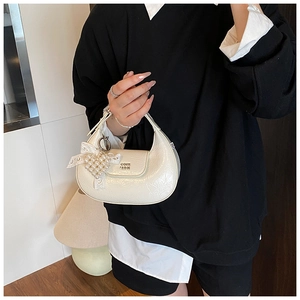 Detail of off-white glossy dumpling bag with pearl lace heart charm and logo