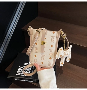 Close-up of cream PU leather phone bag with teddy bear pattern and golden buckle