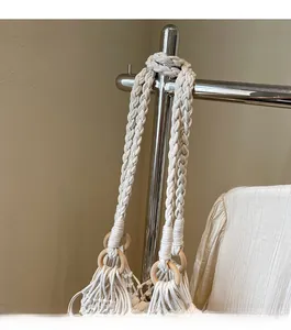 Detail of hand-woven shoulder strap with smooth wooden ring on off-white bucket bag