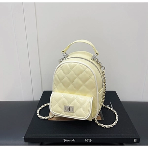 Detail of quilted pale yellow mini backpack with silver twist-lock and chain straps