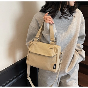 Détail d'un sac à main en nylon beige clair avec poignée et finitions en métal argenté