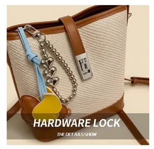 Detail of silver square metal lock and cute heart bead charms on beige woven bucket bag