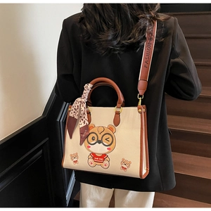 Detail of the cream bear tote bag featuring leopard scarf and wide logo strap