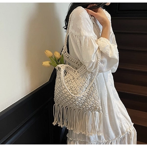 Detail of white bohemian woven tote bag featuring hollow knit texture and long tassels