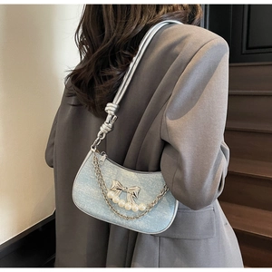 Detail of light blue glitter underarm bag with silver bow, pearls and chain detail