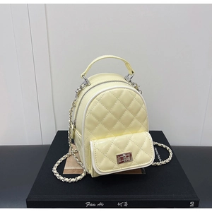 Detailed macro view of pale yellow quilted mini backpack with silver metal chain and twist lock