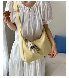 Close-up of lemon yellow dumpling bag in crocodile texture with a cute plush bear charm